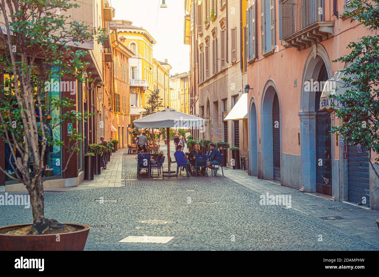 Brescia, Italia, 11 de septiembre de 2019: Típica calle estrecha italiana con edificios antiguos tradicionales, calle adoquinada y restaurante de calle con personas sentadas, centro histórico de la ciudad, Lombardía Foto de stock