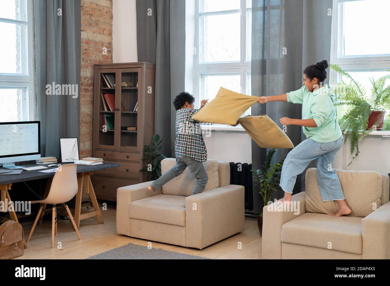 Dos lindos hermanos de raza mixta en la almohada de ropa de casualwear  lucha sobre suave sillones Fotografía de stock - Alamy