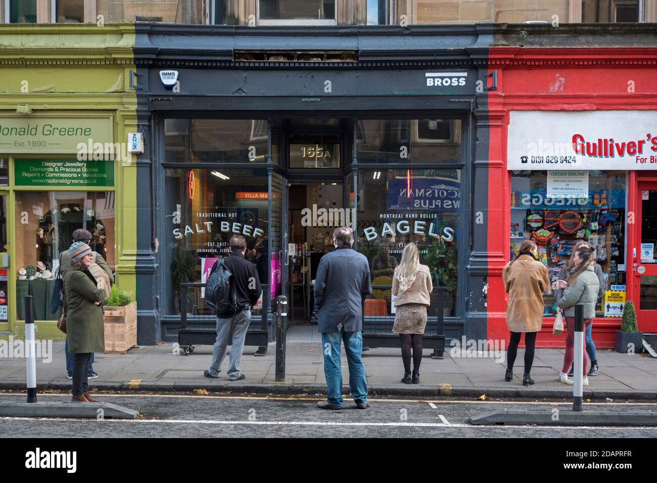 Una cola socialmente distanciada durante la pandemia de coronavirus esperando fuera de una tienda de bagels en Bruntsfield, Edimburgo, Escocia, Reino Unido. Foto de stock