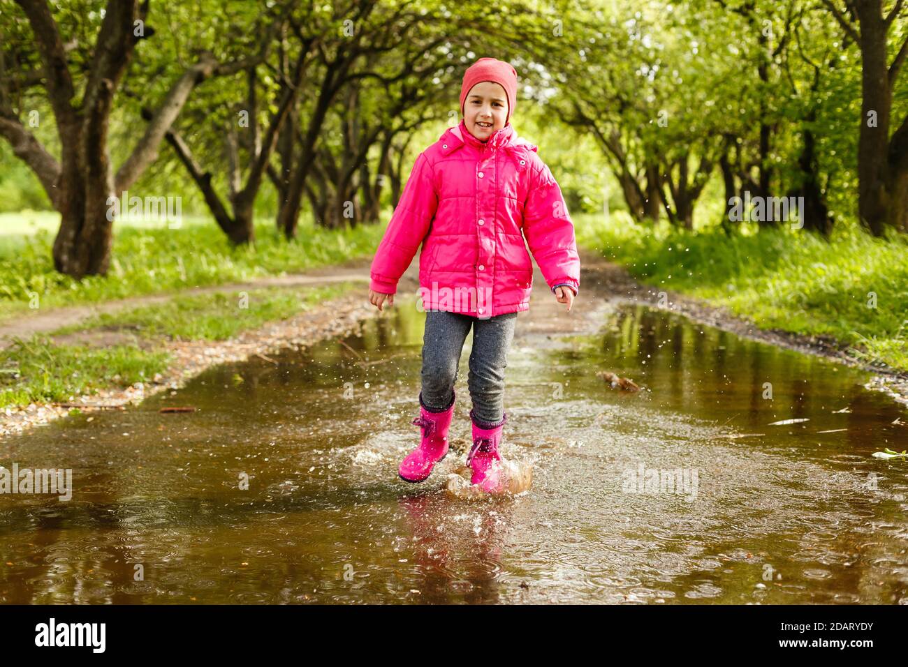 linda niña con botas de lluvia saltando en un charco Fotografía de stock -  Alamy