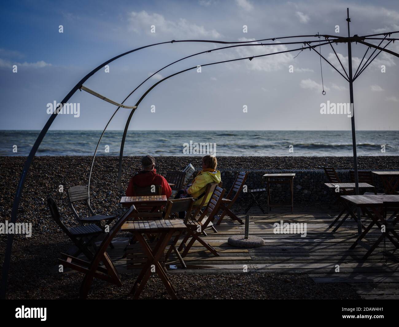 Una pareja se sienta en los asientos frente al mar de la cafetería "Costa" cerrada en un domingo soleado de noviembre durante Lockdown 2 el domingo 15 de noviembre de 2020, Worthing Foto de stock