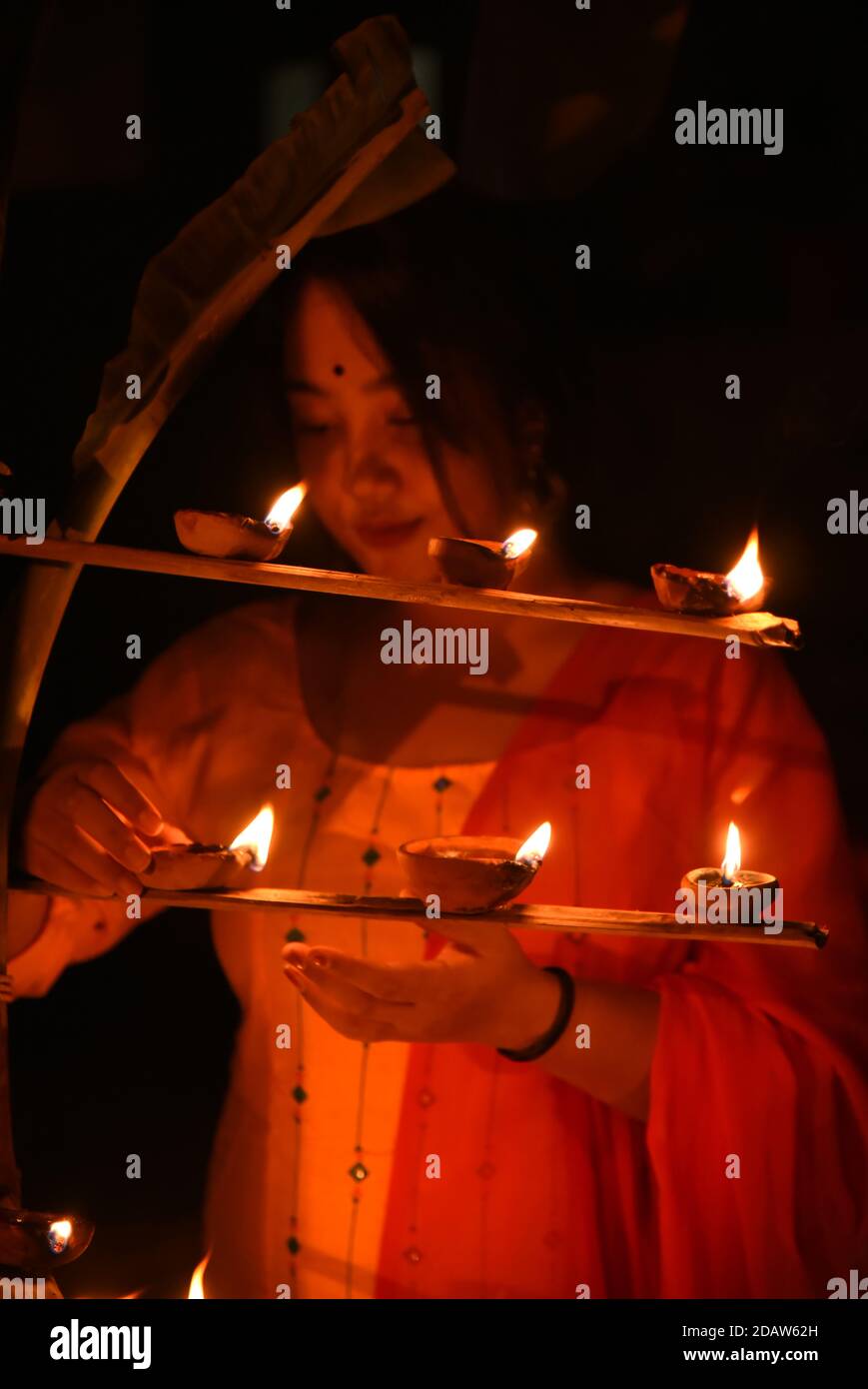 Guwahati, Assam, India. 15 de noviembre de 2020. Las mujeres de Assamese  encienden las lámparas de los oídos con ocasión de la celebración de  Diwali, el festival hindú de la luz en