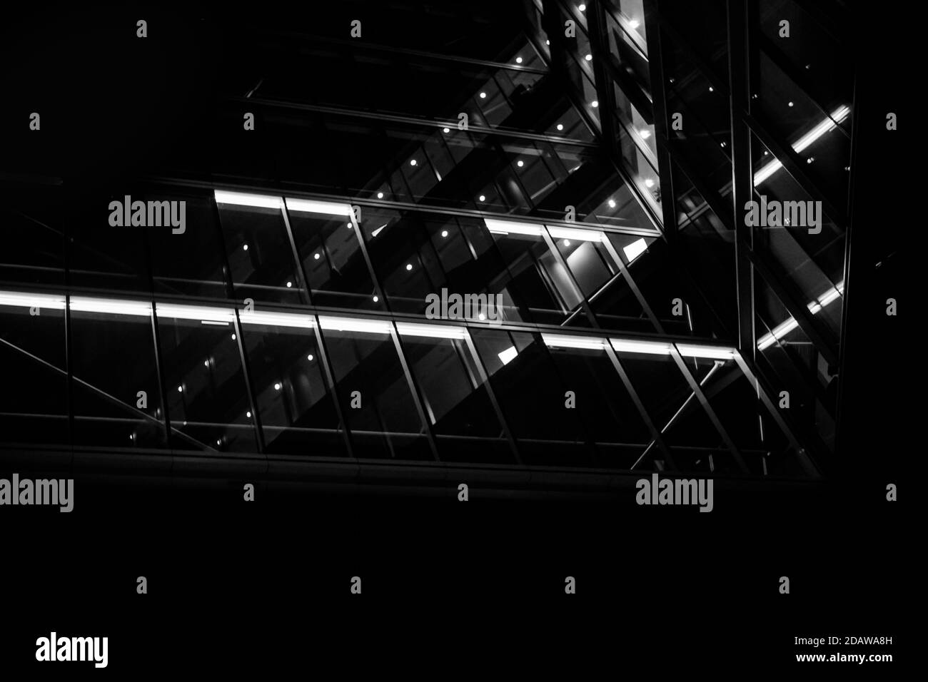 Imagen monocromática en blanco y negro mirando a la oficina de cristal edificio por la noche Foto de stock