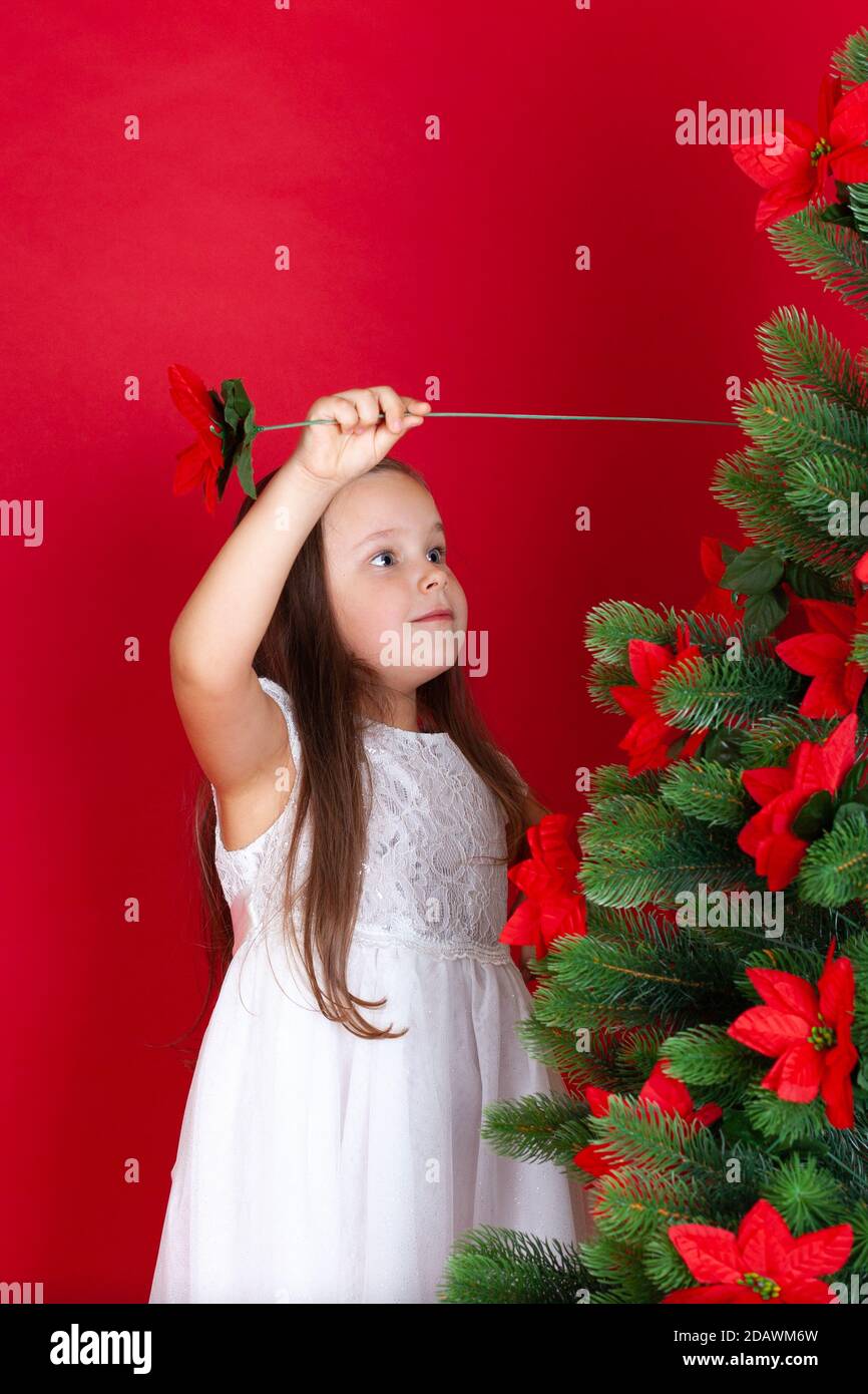 Niña de imitación en blanco vestido palos flores artificiales en árbol de  Navidad, aislado sobre fondo rojo con espacio para el texto Fotografía de  stock - Alamy