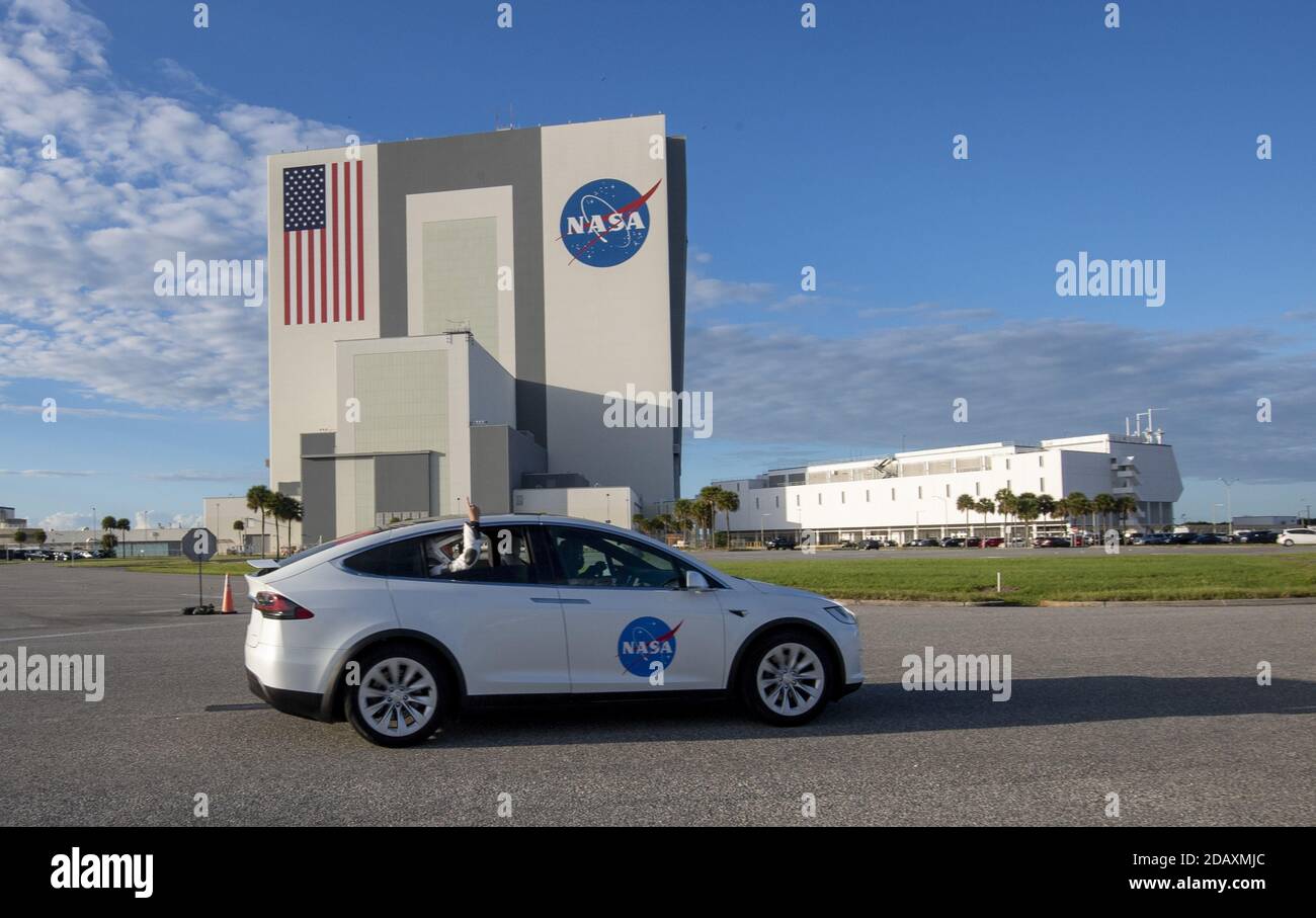 Los astronautas ondean desde el Tesla Model X mientras pasan por el edificio de montaje de vehículos (VAB) de camino a bordo de la Crew-1 en lo alto de un cohete Spacex Falcon 9 para prepararse para su lanzamiento desde el complejo 39A en el Kennedy Space Center en Florida el domingo, 15 de noviembre de 2020. Se espera que la nave espacial Crew Dragon se lance por la noche con cuatro astronautas a bordo dirigidos a la Estación Espacial Internacional, y está atendida por astronautas de la NASA, el Comandante Michael Hopkins, el piloto Victor Glover, el Especialista en Misión Shannon Walker y el Especialista en Misión de la Agencia Japonesa de exploración Aeroespacial (JAXA), Soichi Noguchi Foto de stock