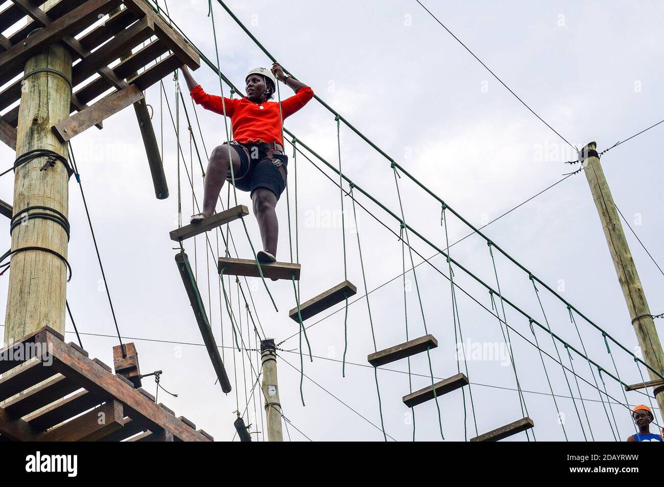 Hope Ayite hace el nivel 2 de un desafío de cuerdas en el Parque Extreme Adventure en Busiika, una zona residencial a unos 32 kilómetros (20 millas) al norte de Kampala, Uganda. Foto de stock