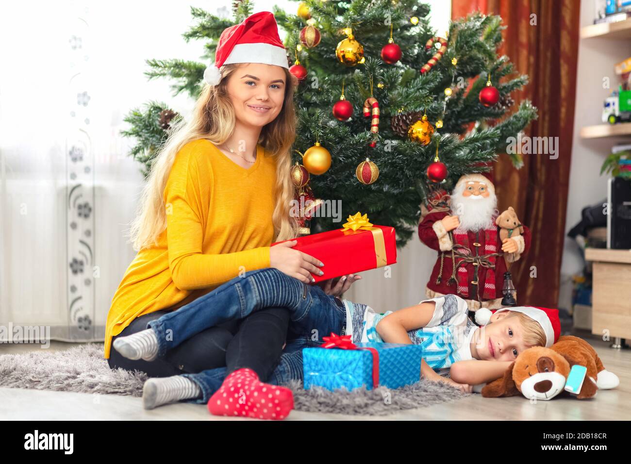 Feliz madre soltera con niño celebrando la Navidad en casa compartiendo presenta Foto de stock
