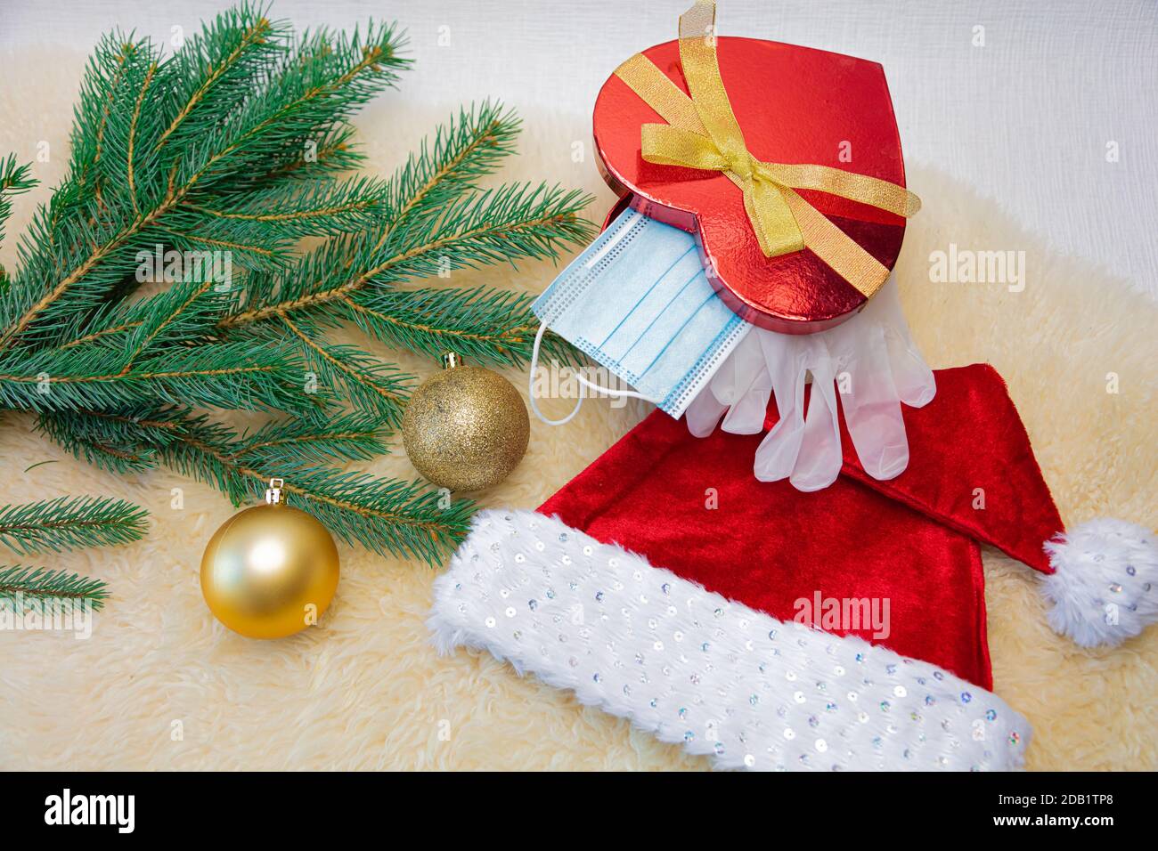 La caja de regalo contiene una máscara médica y guantes de látex, una rama  de abeto y adornos navideños y un sombrero de Navidad. Concepto,  felicitaciones Feliz año Nuevo 2021. Sobre un