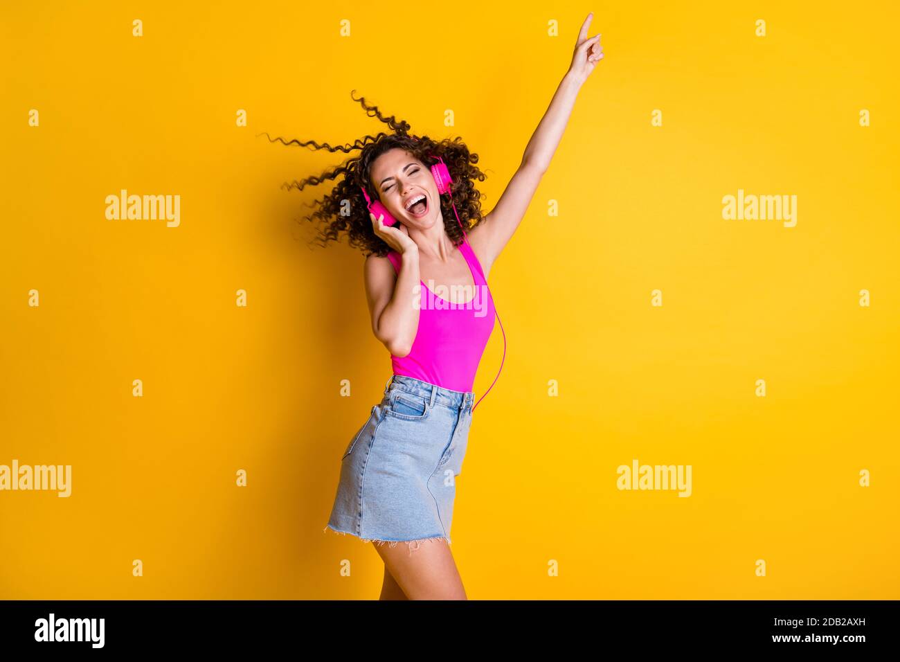 Foto de perfil de mujer loca y fría con pelo ondulado volar aire viento  soplando figura flaca escuchar tecnología moderna los auriculares llevan  rosa camiseta de tirantes mini falda denim Fotografía de