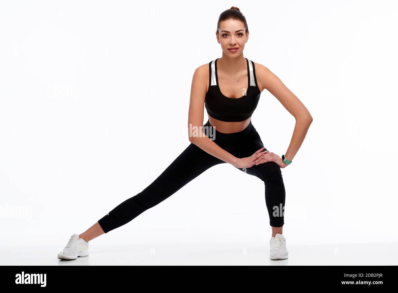 Ajuste fuerte mujer de fitness en ropa deportiva estirar las piernas sobre  fondo blanco aislado. Instructora de deporte femenina haciendo ejercicio  físico Fotografía de stock - Alamy