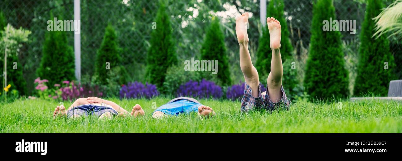 Familia relajándose sobre hierba verde, descalzo tumbado y mirando al cielo Foto de stock