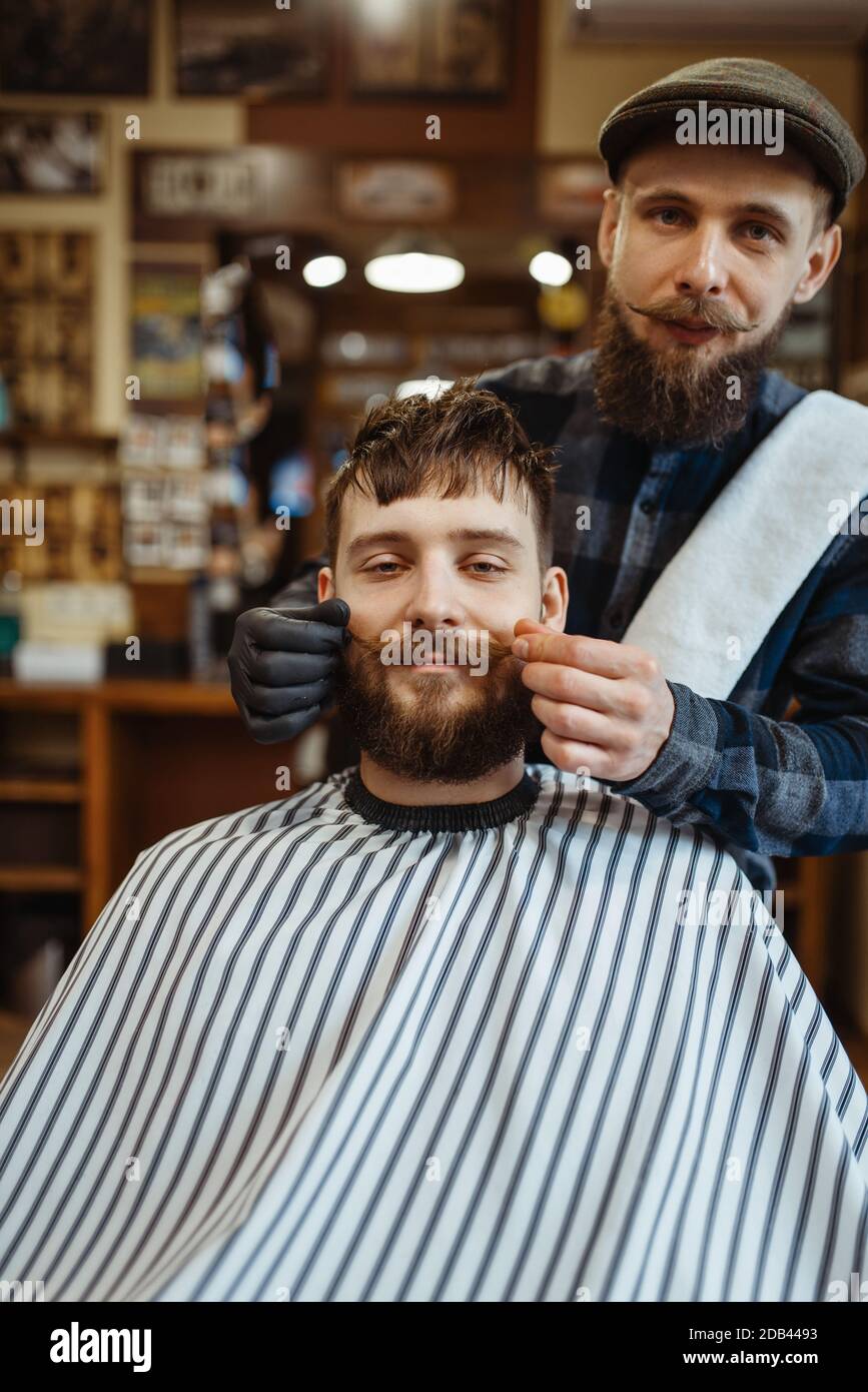 Barbería y cliente con bigote, corte de barba de la vieja escuela. La  peluquería profesional es una ocupación de moda. Peluquería masculina y  cliente en la calle retro Fotografía de stock -