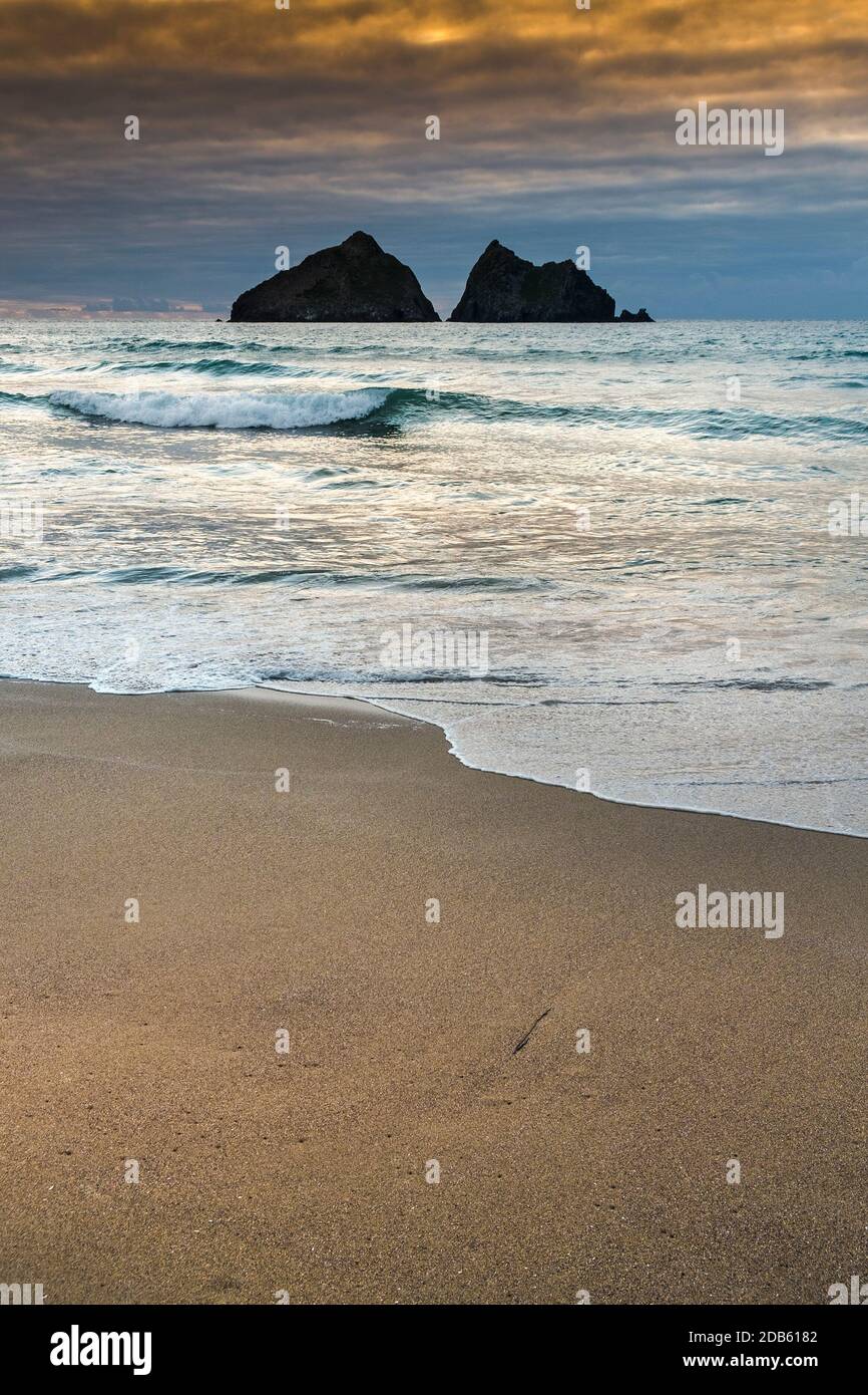 Puesta de sol en Holywell Beach con Gull Rocks en la distancia en Cornwall. Foto de stock