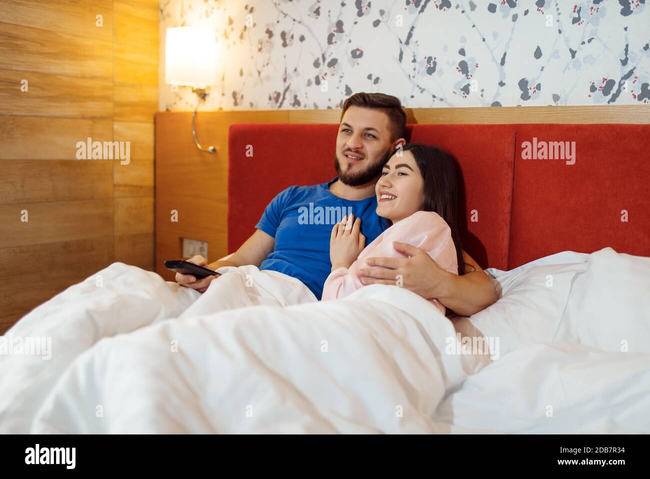 Pareja de amor en pijama acostado en la cama y viendo la televisión en casa, Buenos días. Relación armoniosa en la familia joven. Hombre y mujer descansando juntos Fotografía de stock - Pareja de amor en pijama acostado en la cama y viendo la televisión en casa, Buenos días. Relación armoniosa en la familia joven. Hombre y mujer descansando juntos Fotografía de stock -