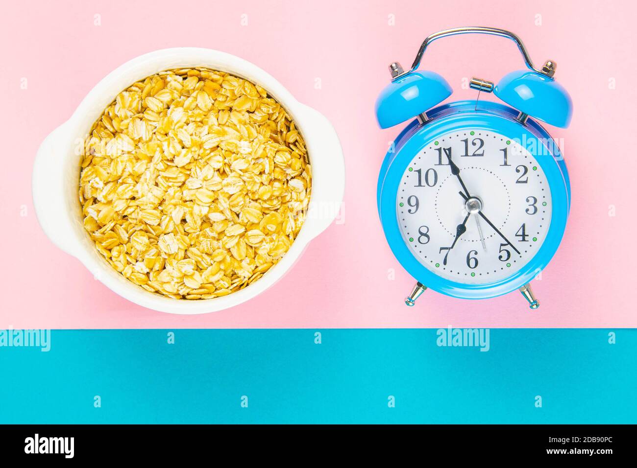 Reloj despertador azul con avena sobre fondo rosa y azul. Concepto de  nutrición saludable. Vistas superiores con espacio libre Fotografía de  stock - Alamy