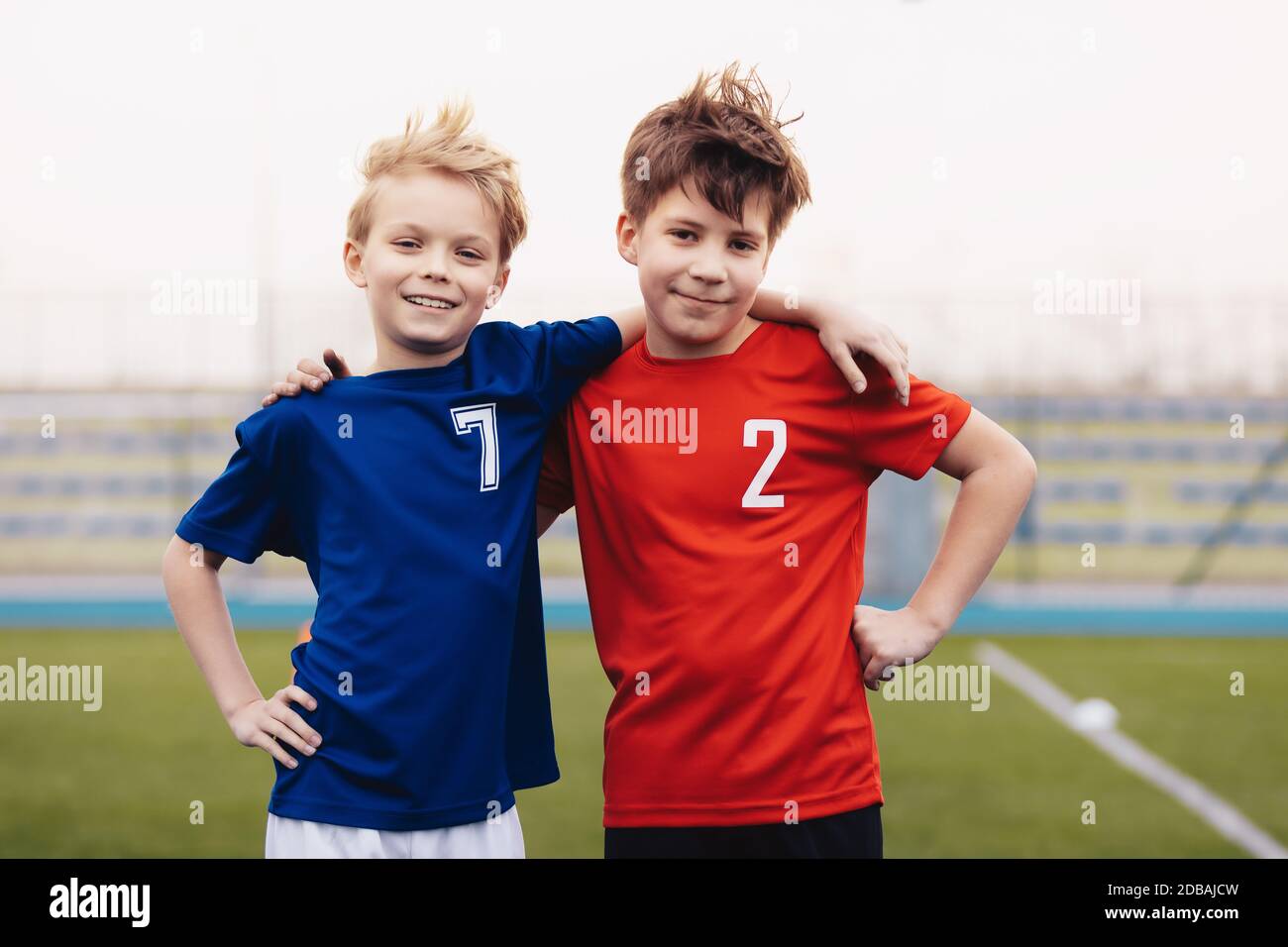 Dos chicos felices aire libre en ropa deportiva. Niños sonriendo a cámara. Niños de pie en un campo de césped deportivo. Educación deportiva para niños Fotografía de stock -