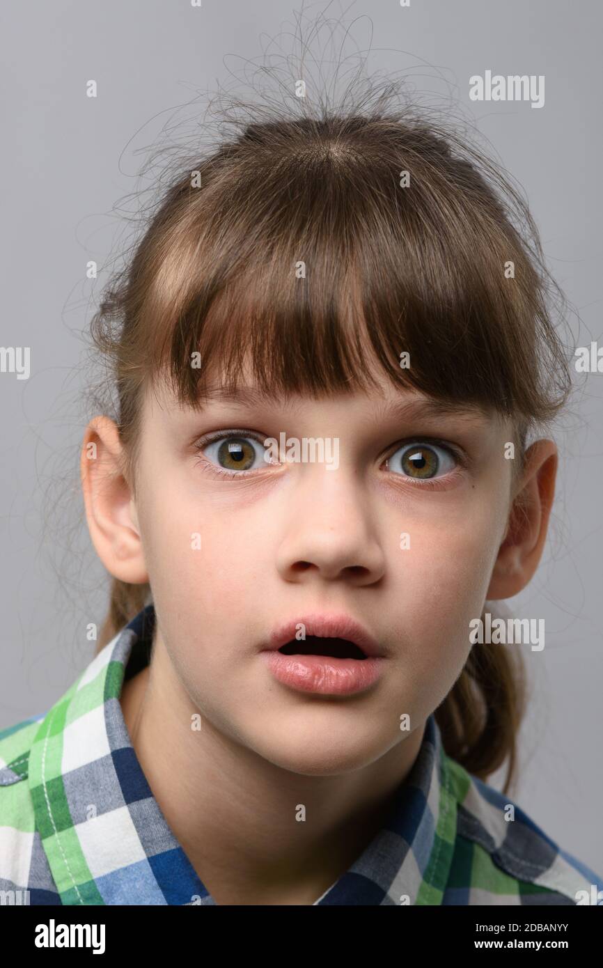 Retrato de una niña de diez años muy sorprendida con ojos abultados y boca abierta, aspecto europeo, primer plano Foto de stock