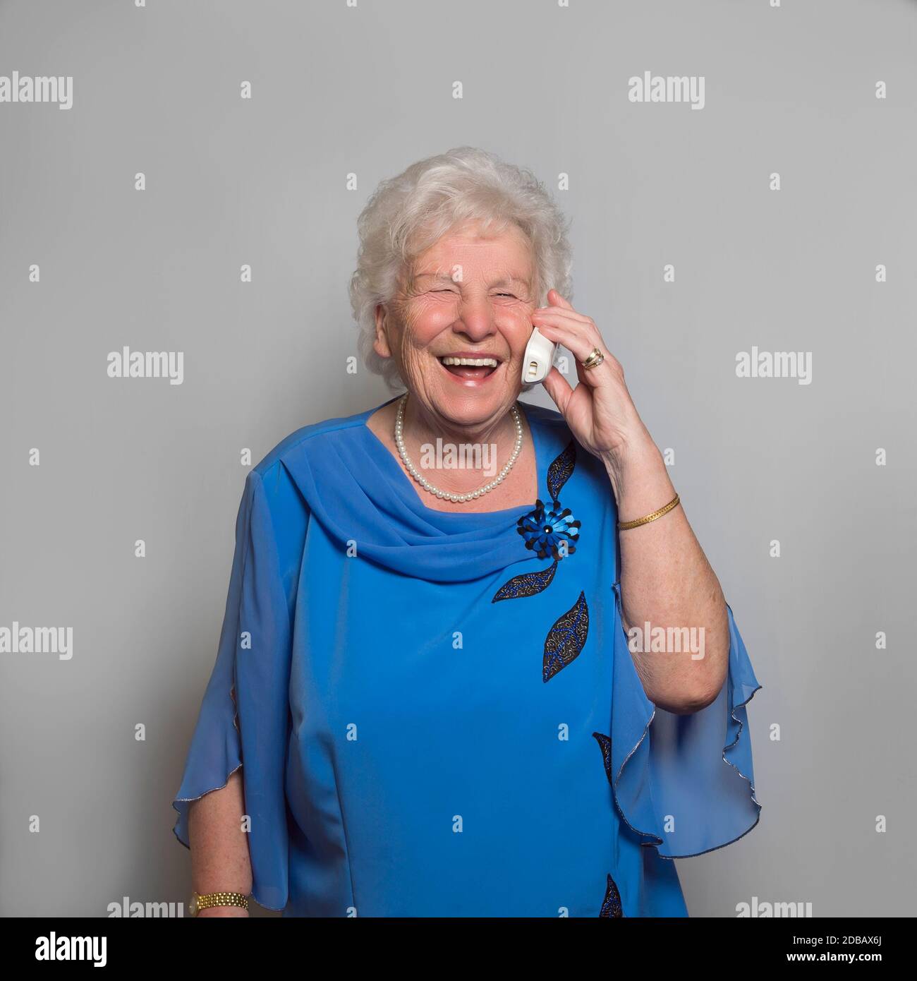 mujer de 80 años al teléfono. Está feliz de recibir llamadas durante el aislamiento de la prohibición de contacto de Corona Pandémica. Foto de stock