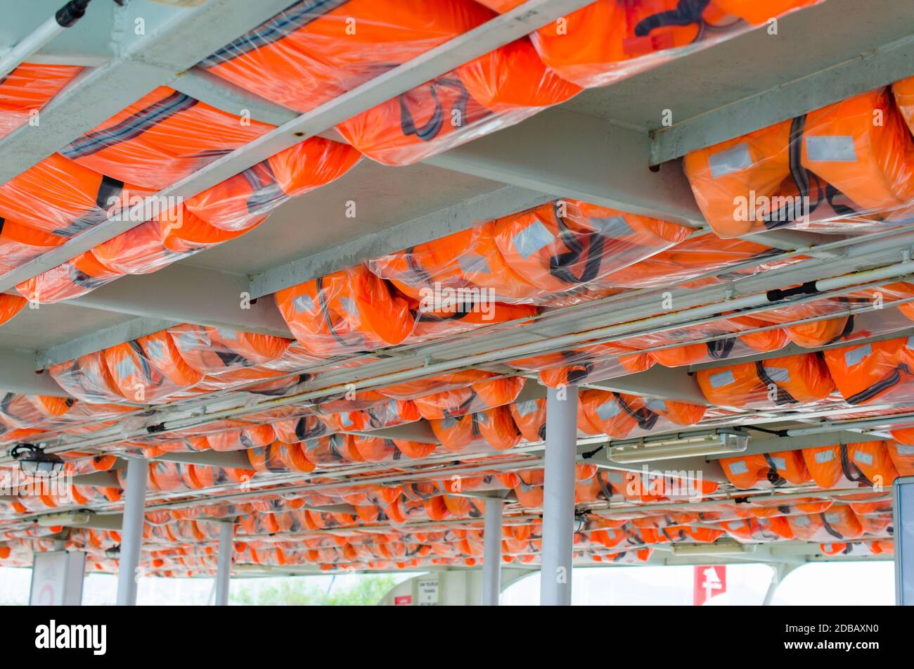 Chalecos salvavidas naranjas o chaleco en perchas para el techo listos para usar en el barco de transporte. Equipo de seguridad en un barco de placer. Foto de stock