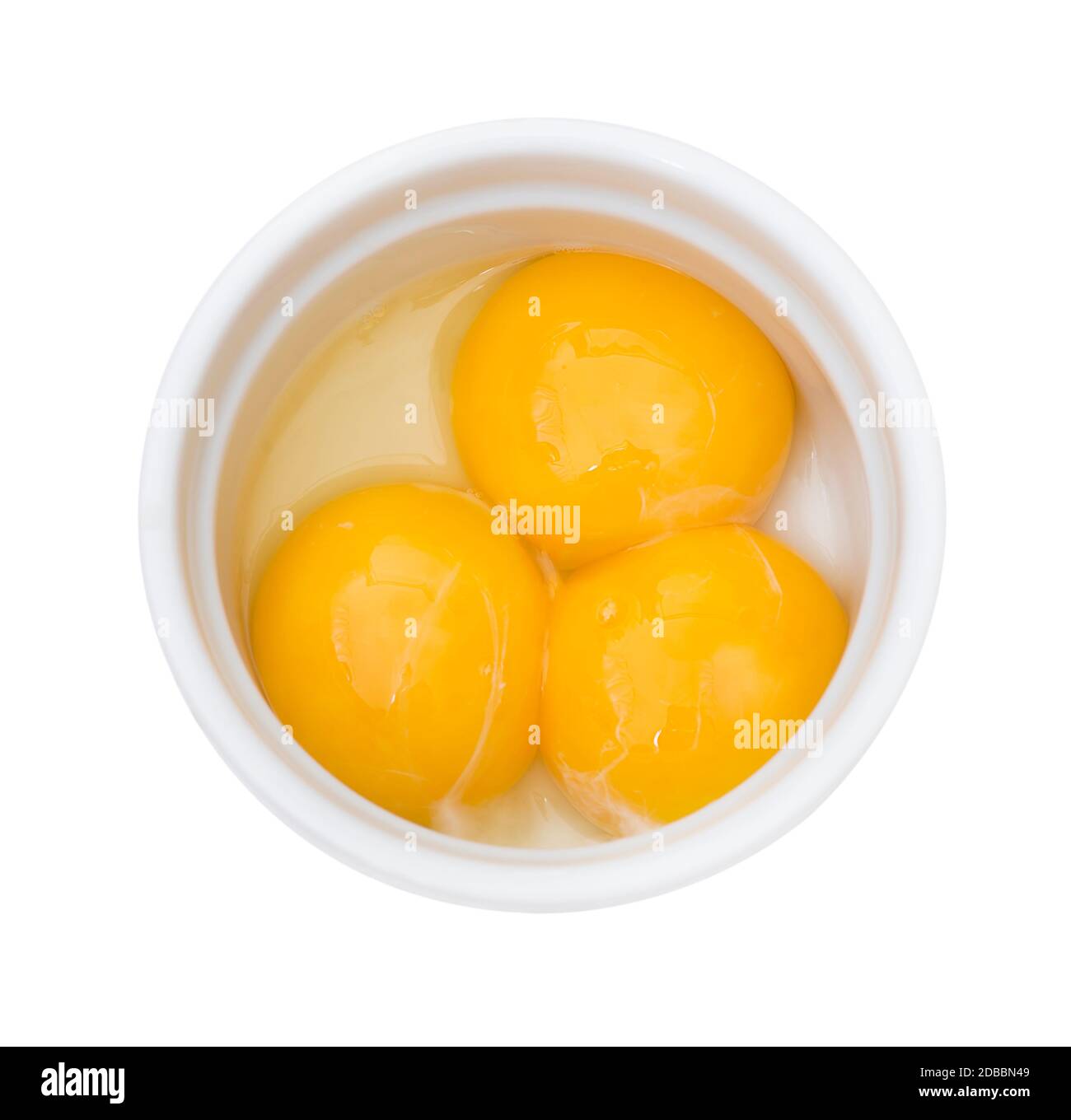 Yemas de huevo amarillo brillante en un tazón blanco aislado sobre fondo blanco Foto de stock