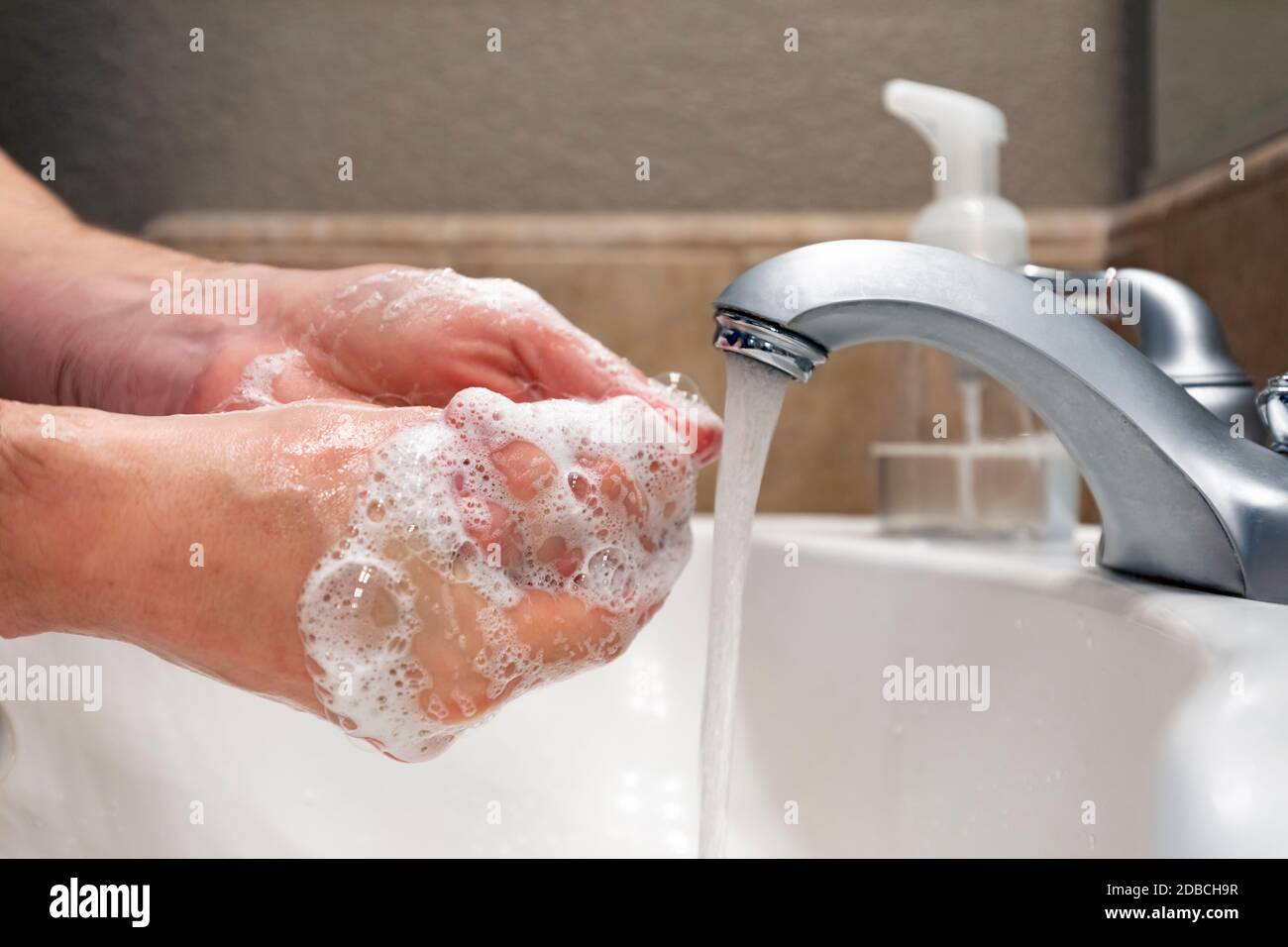 Lavarse las manos con agua y jabón en el lavabo del baño, protección contra virus y bacterias, higiene para mantenerse saludable Foto de stock