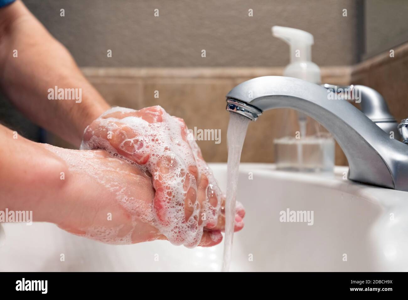 Lavarse las manos con agua y jabón en el lavabo del baño, protección contra virus y bacterias, higiene para mantenerse saludable Foto de stock