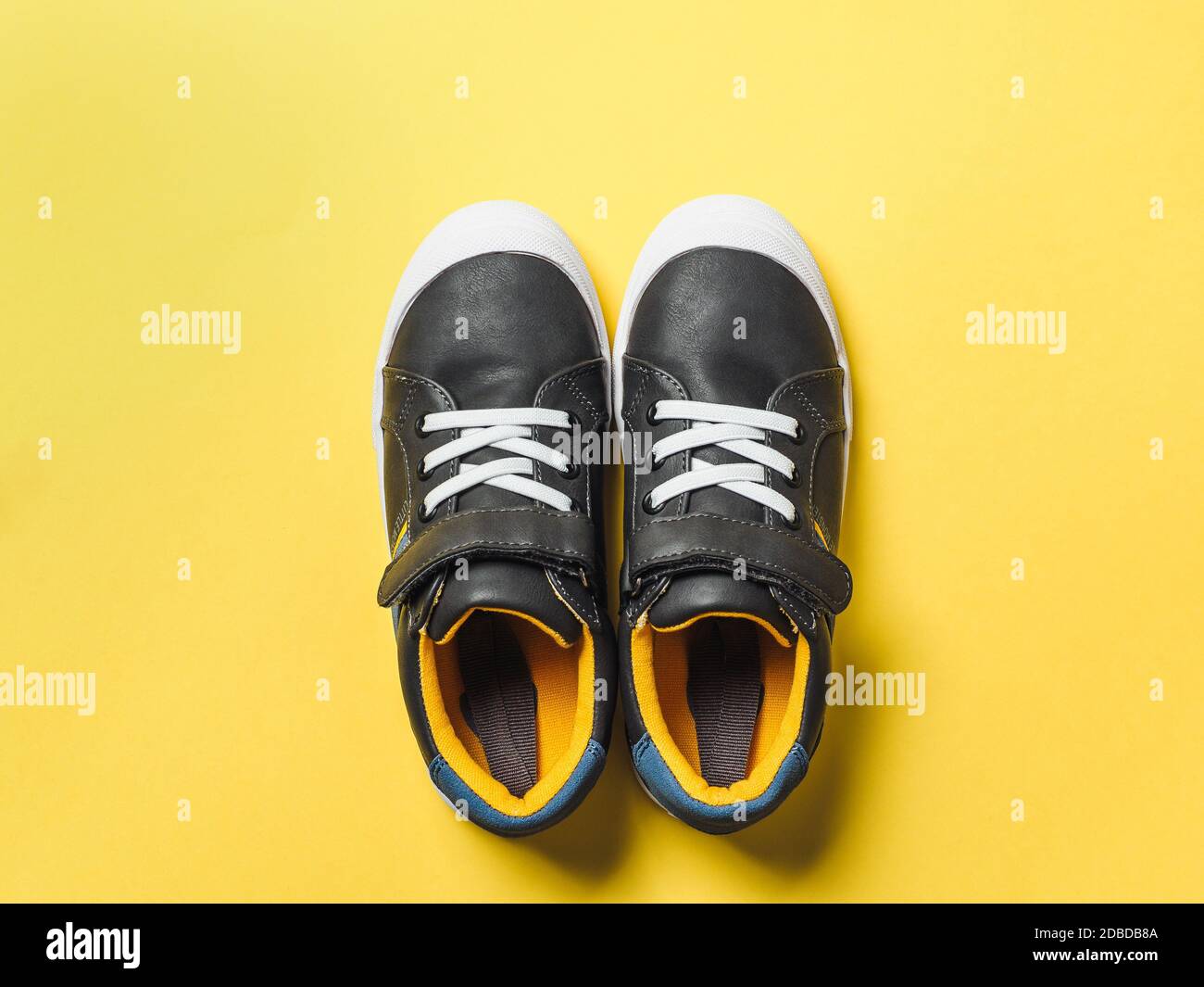 dos sneakers para niños nuevos o adultos sobre fondo amarillo, vista  superior. Zapatos planos de color gris y amarillo o mostaza en color  brillante negro Fotografía de stock - Alamy