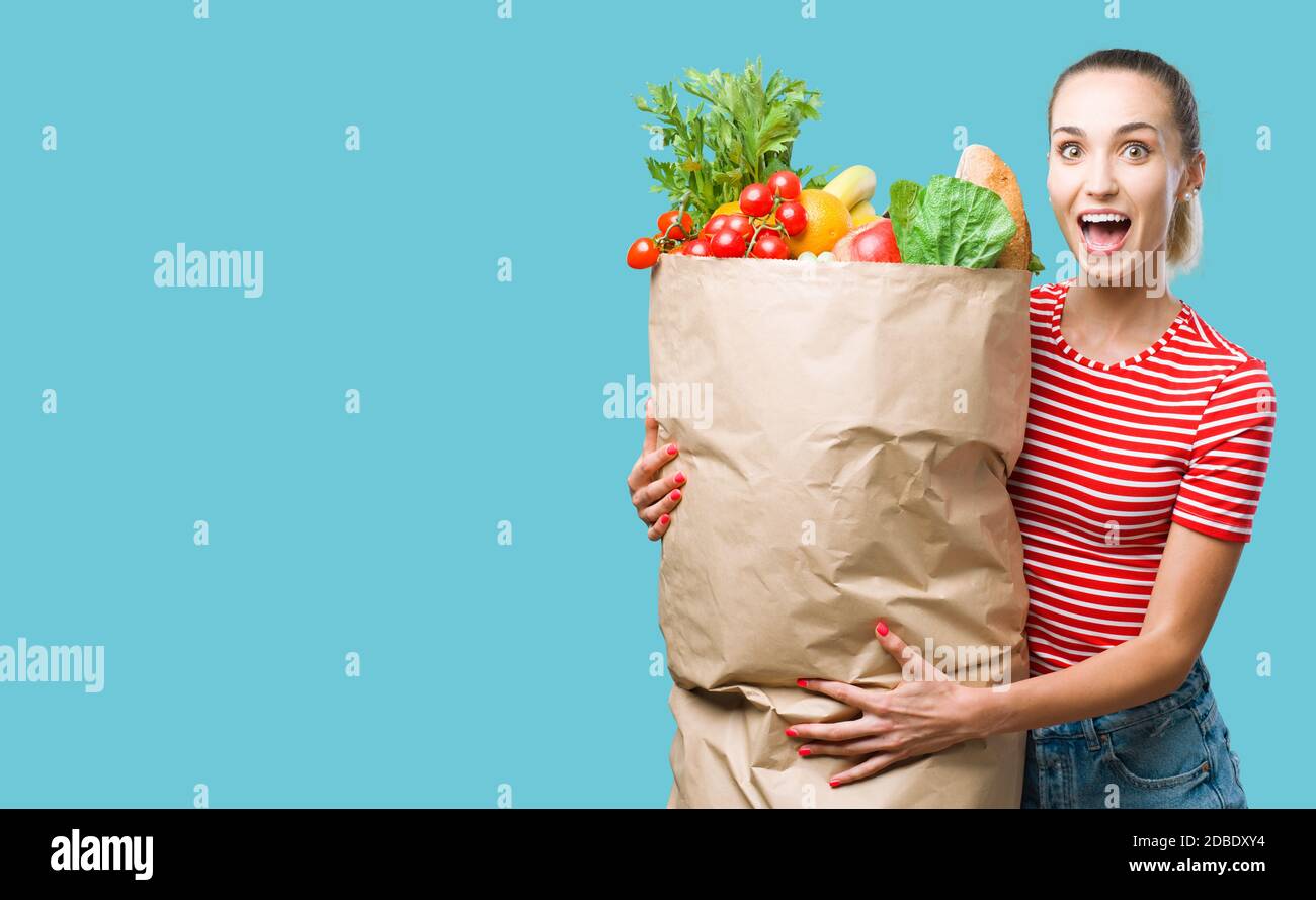 Alegre mujer joven feliz sosteniendo una enorme bolsa de comestibles llena de verduras frescas deliciosas, compras de comestibles y concepto de alimentación saludable Foto de stock