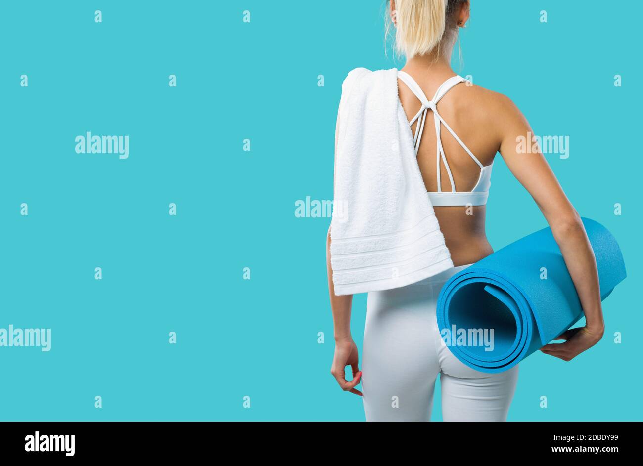 Hermosa mujer deportiva posando y sosteniendo una alfombra de ejercicio, fitness y concepto de entrenamiento Foto de stock