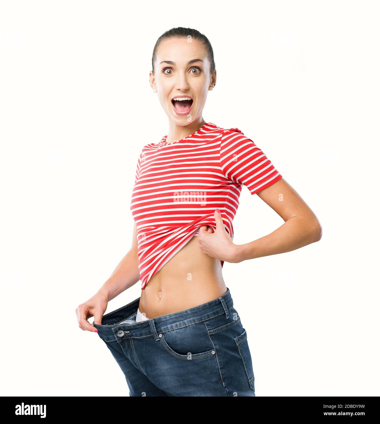 Mujer feliz mostrando su pérdida de peso exitosa, sus jeans están sueltos y es delgado, pérdida de peso y concepto de fitness Foto de stock