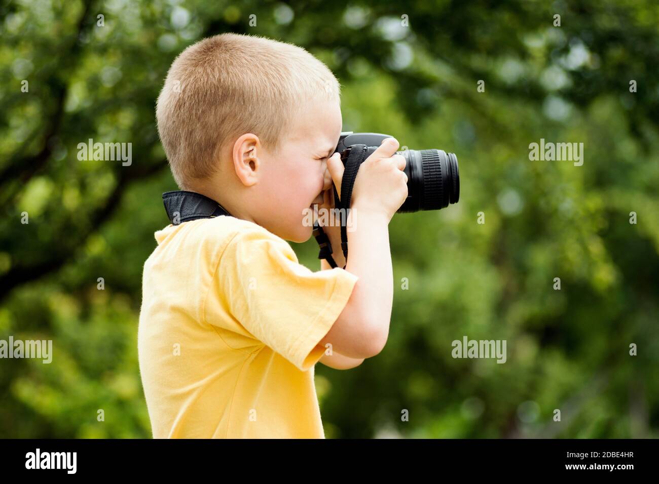 El pequeño fotógrafo de pelo rubio está fotografiando al aire libre sobre  fondo verde Fotografía de stock - Alamy