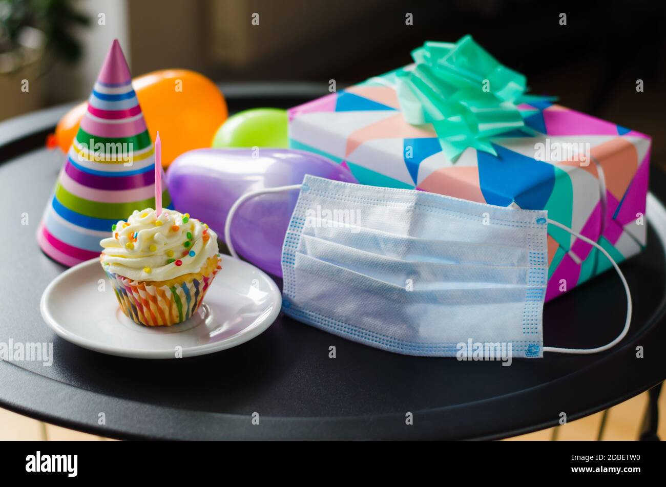 Cumpleaños en cuarentena en aislamiento. Cupcake de cumpleaños con vela,  máscara, regalos y accesorios de vacaciones. Distancia social Fotografía de  stock - Alamy