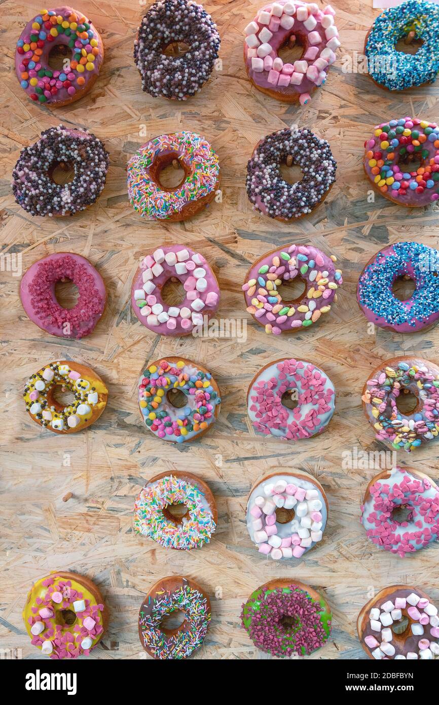 Muchos Donuts De Colores Diferentes Yacen En Un Soporte De Madera Imagen de  archivo - Imagen de colorido, color: 227191491