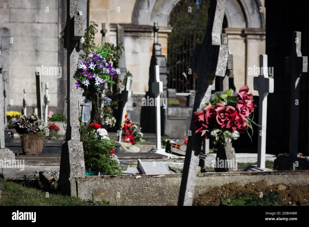 Cruces de piedra honrando con ramos de flores en el cementerio en el