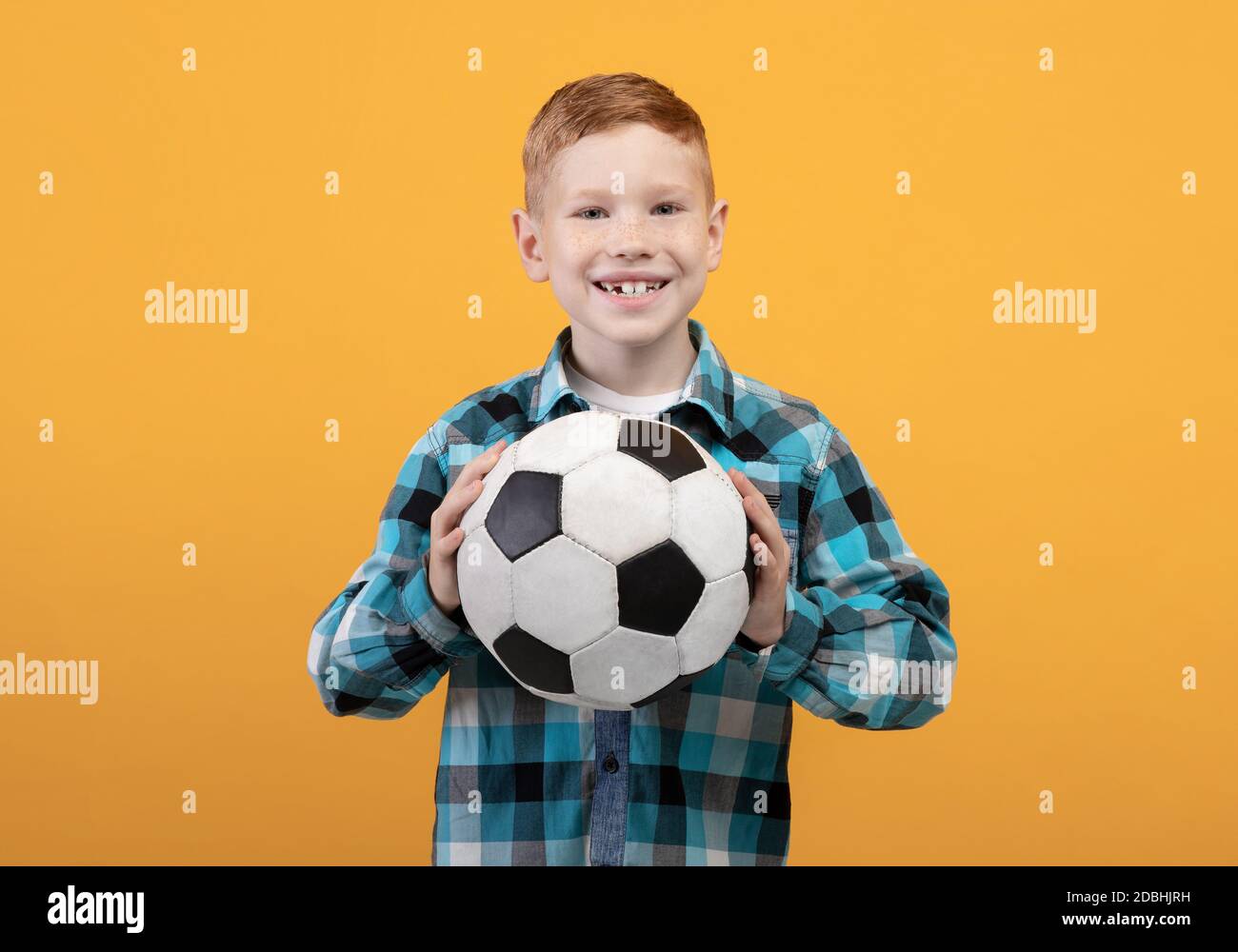 Niño pequeño con la pelota de fútbol sobre fondo amarillo Fotografía de  stock - Alamy