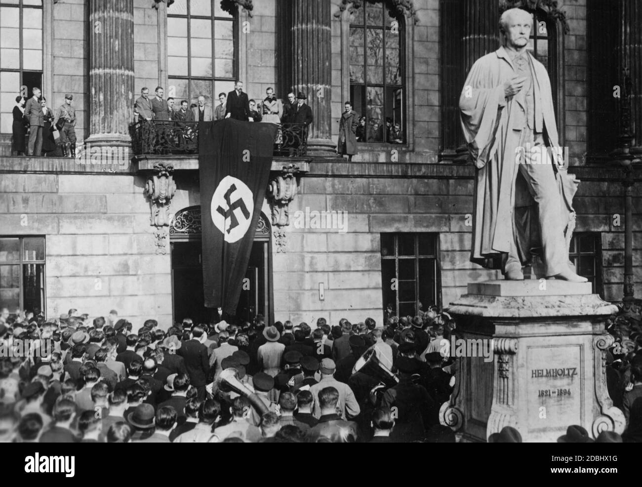 El Rector Eugen Fischer da un discurso en el balcón de la Friedrich-Wilhelms-Universidad de Berlín durante el rally del cuerpo estudiantil de Berlín en el jardín frontal de la universidad. A la derecha, el monumento de Hermann von Helmholtz. Foto de stock
