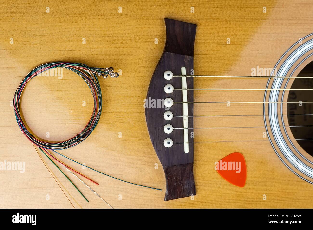 selección de guitarra amarilla metida en cuerdas de guitarra acústica de oro  en un tablero de madera oscura Fotografía de stock - Alamy