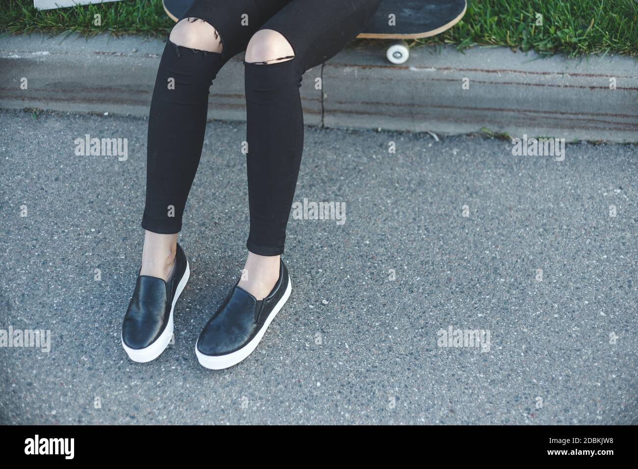 boxeo Saludo soltar Mujer joven en negro jeans, zapatillas, sentados en el suelo junto a su  patineta afuera Fotografía de stock - Alamy