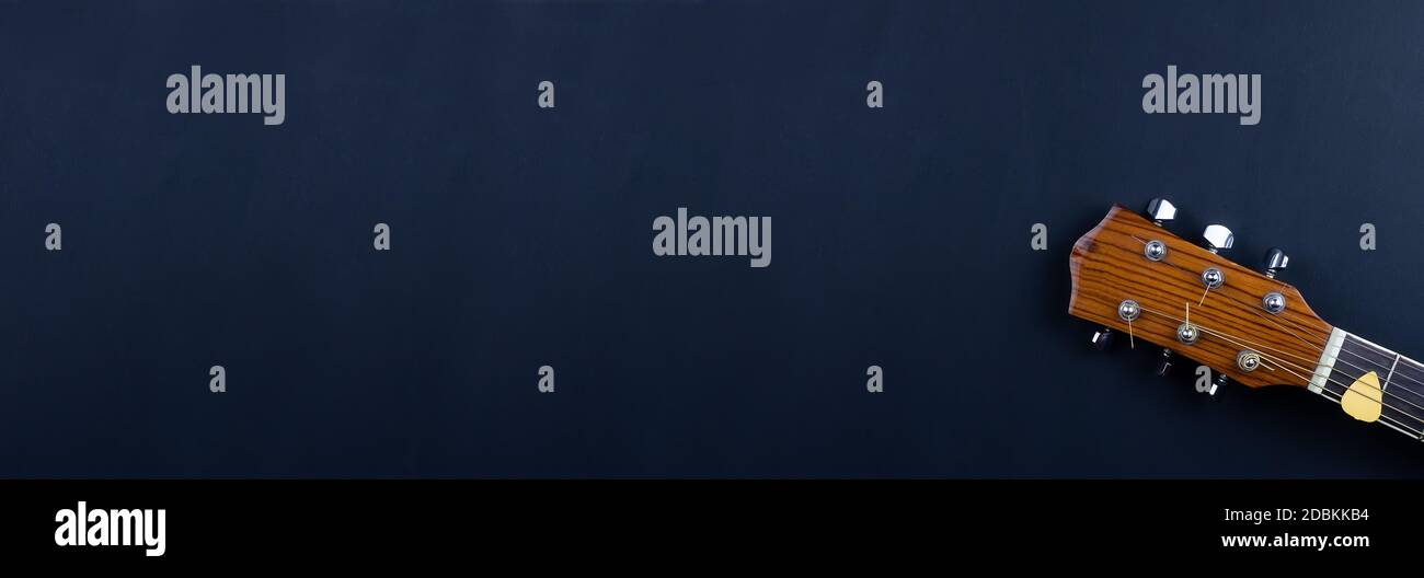 selección de guitarra amarilla metida en cuerdas de guitarra acústica de oro  en un tablero de madera oscura Fotografía de stock - Alamy