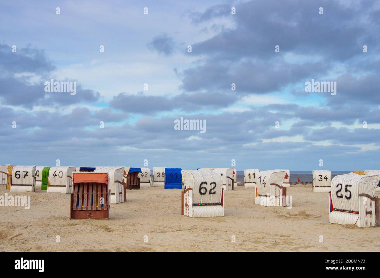 Verlassene Strandkörbe am Strand unter Wolkenhimmel Foto de stock