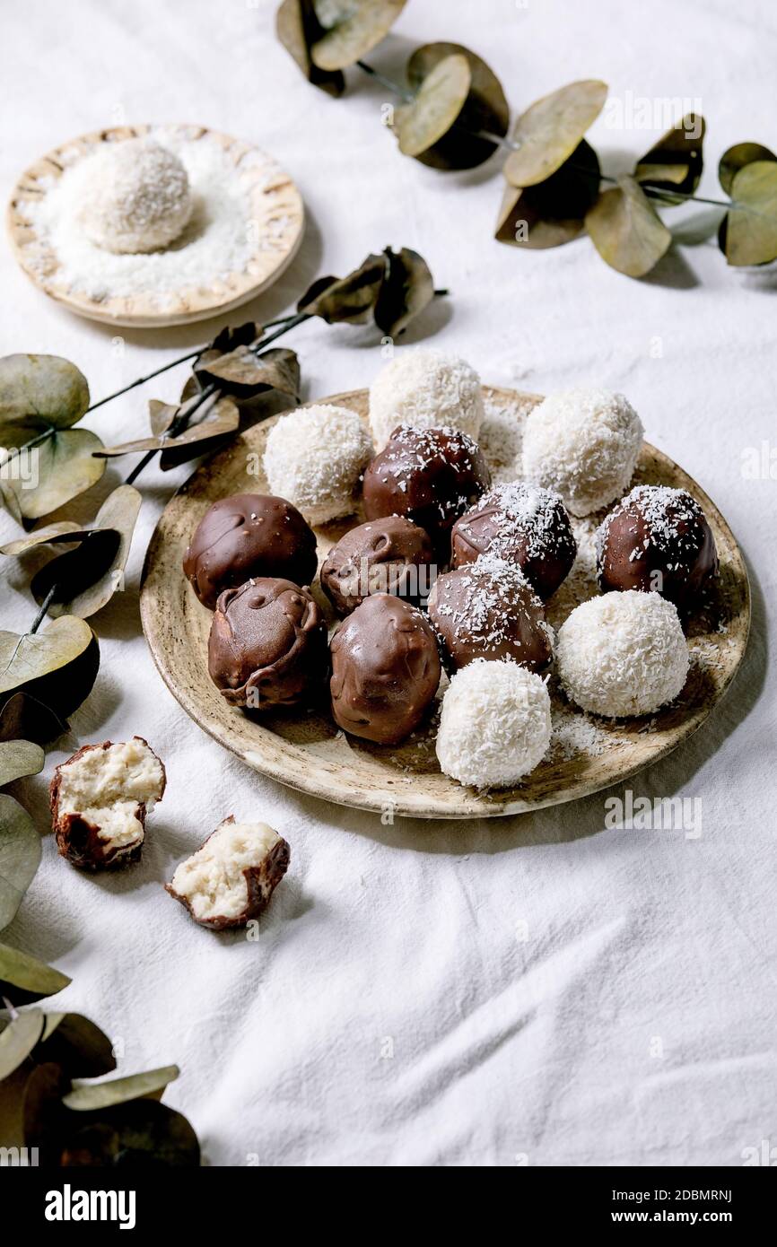 Bolas de chocolate de coco crudo vegano sobre blanco con eucalipto ramas Foto de stock