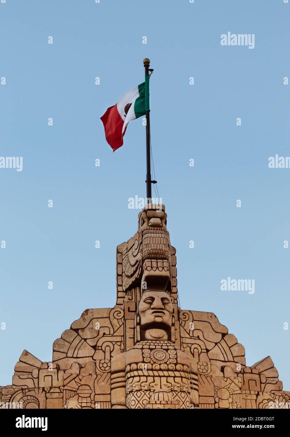 Bandera mexicana sobre un monumento . Monumento a la patria, arquitectura mexicana, punto de referencia turístico en Mérida, Yucatán, México. Foto de stock