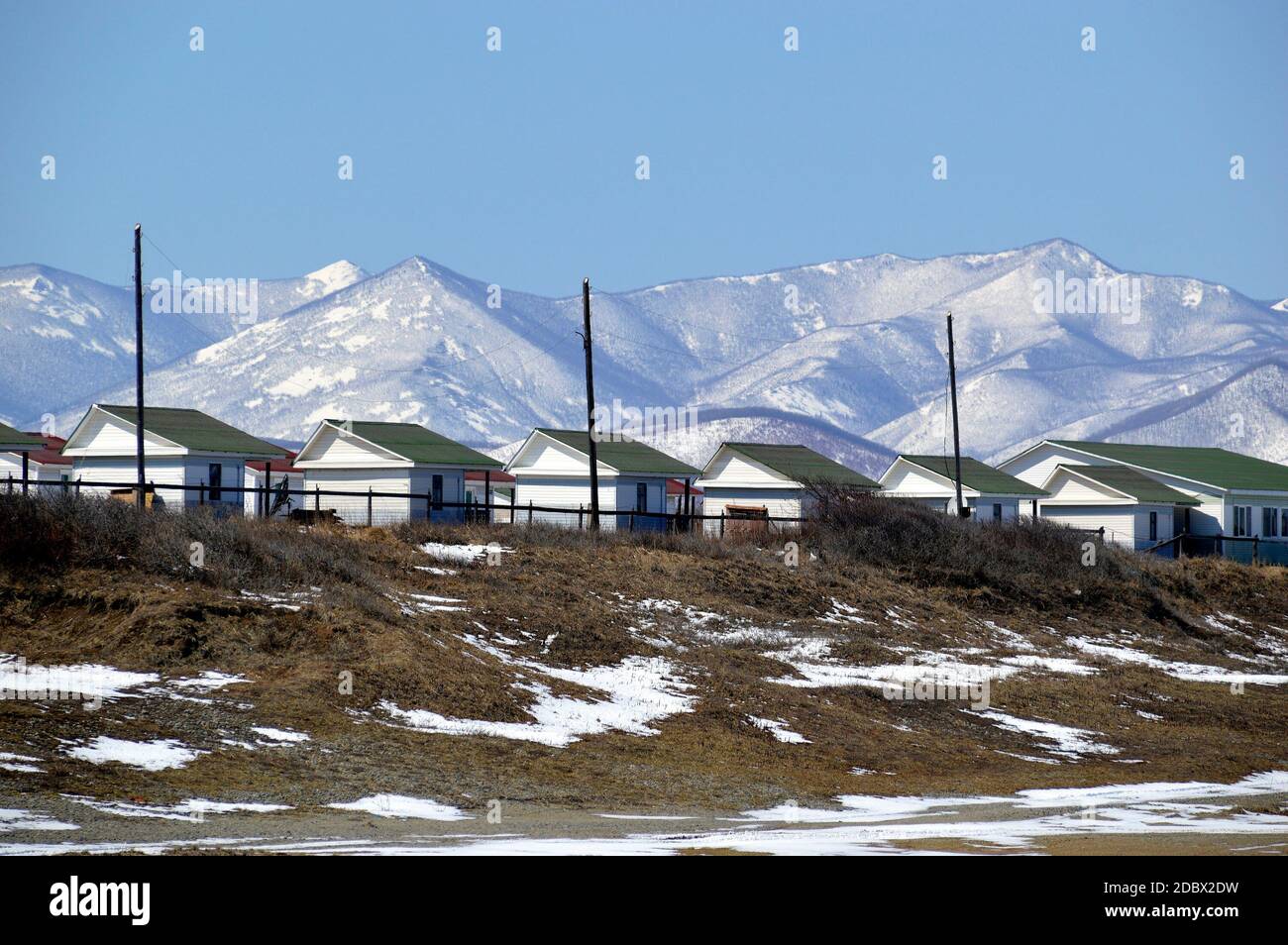 Muchas casas idénticas para acampar y basarse al pie de las montañas nevadas. Extremo Oriente, Rusia Foto de stock