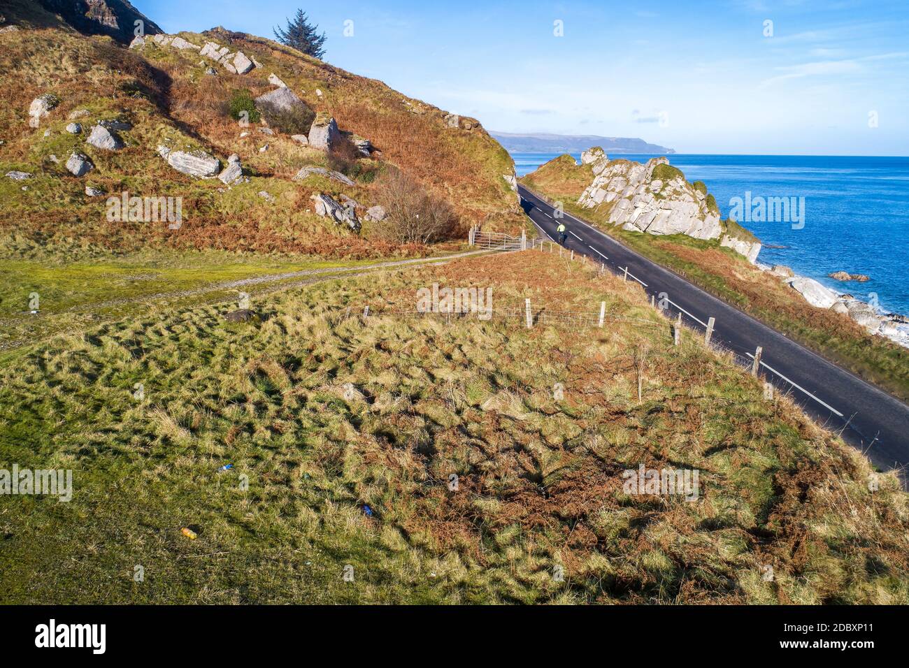 La costa oriental de Irlanda del Norte y la Ruta Costera Causeway con un ciclista. Una de las carreteras costeras más pintorescas de Europa. Vista aérea en invierno Foto de stock