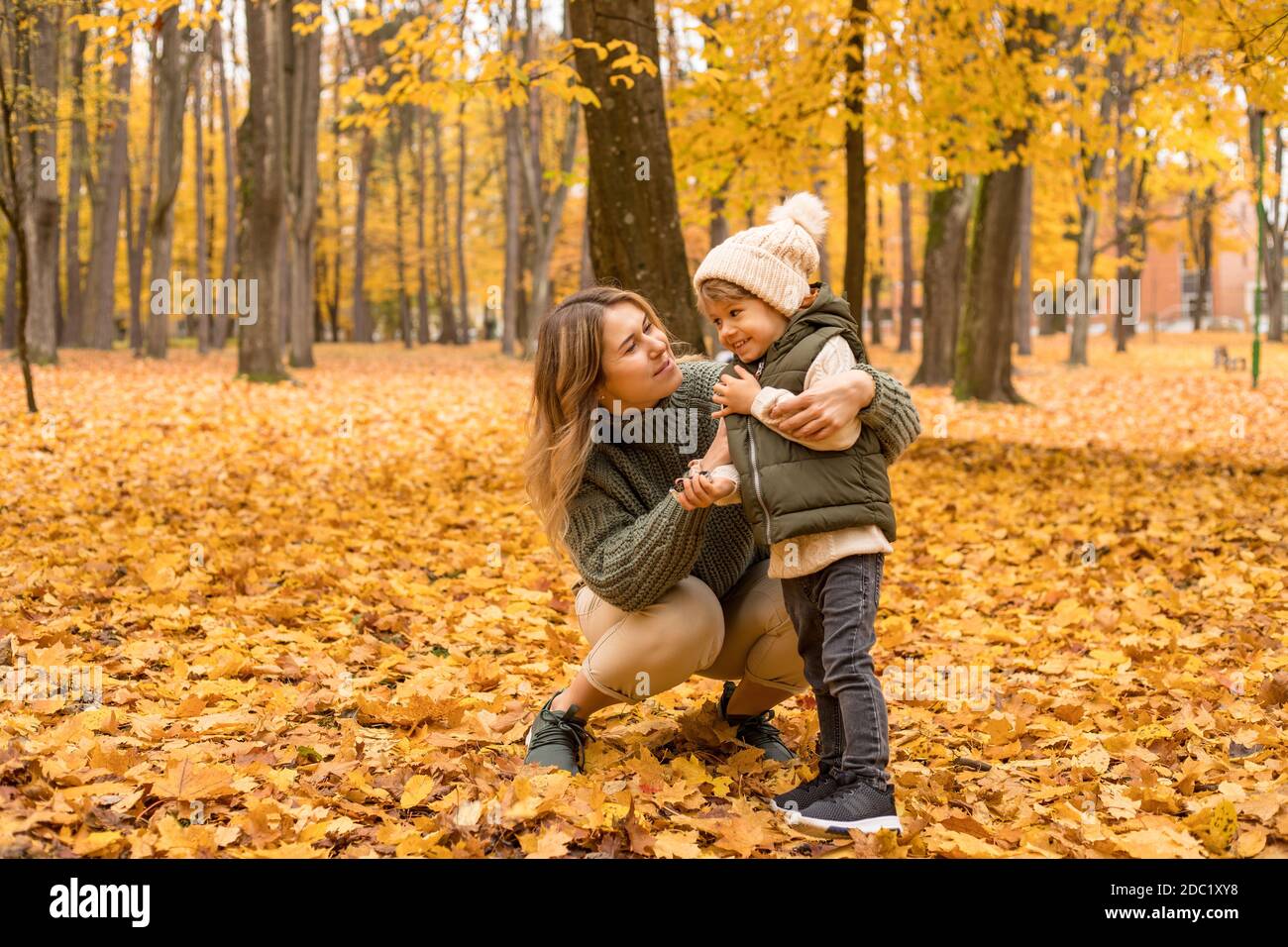 Madre joven con su hijo pequeño en el parque de otoño tienen un ventilador. Follaje amarillo, tiempo al aire libre con los niños. Madre independiente feliz Foto de stock