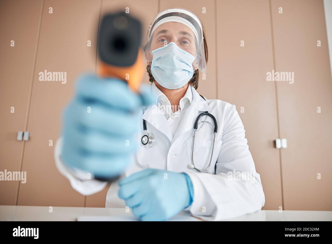 Trabajador médico profesional con un termómetro sin contacto Foto de stock