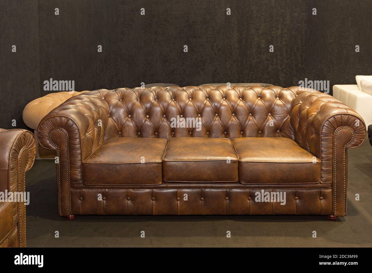 Sofá Chesterfield de cuero marrón de estilo clásico en habitación oscura  Fotografía de stock - Alamy