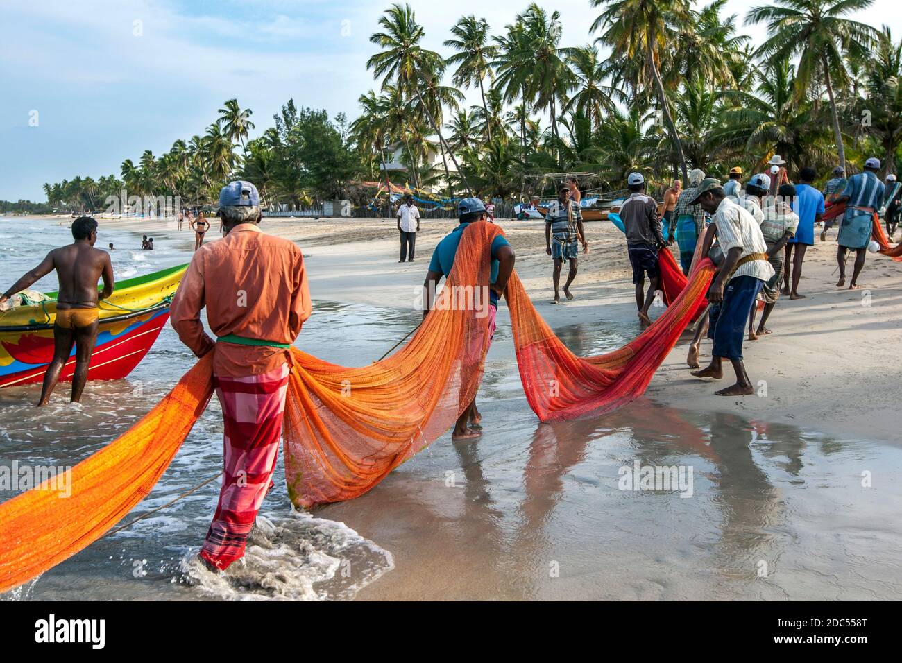 Los pescadores del Sena de la playa arrastran sus redes a la playa de Uppuveli en la costa este de Sri Lanka a última hora de la tarde. Foto de stock