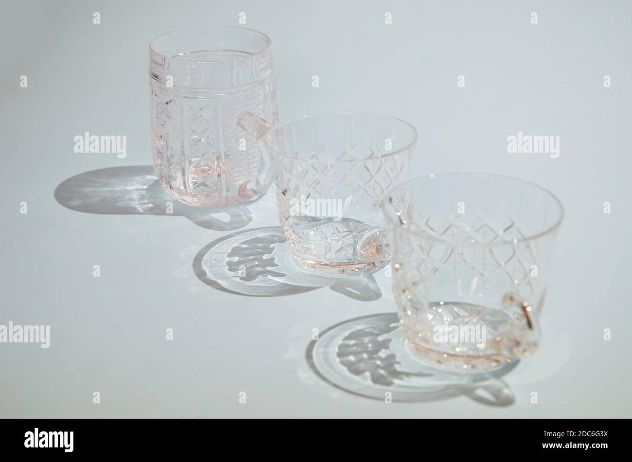 tres copas de cristal transparente con asas en fila sobre un fondo azul Foto de stock