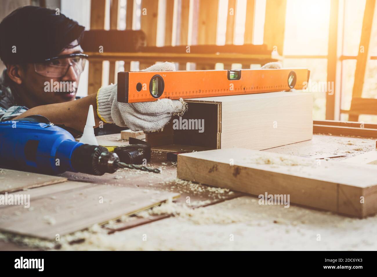 Carpintero trabajando en artesanía de madera en el taller para producir material de construcción o muebles de madera. El joven carpintero asiático utiliza herramientas profesionales para Foto de stock